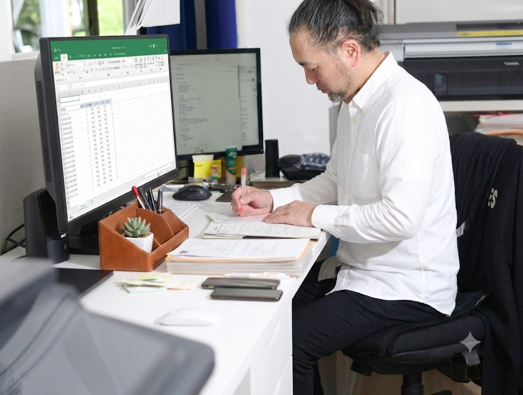 担当デザイナーがExcelで依頼された情報を確認している